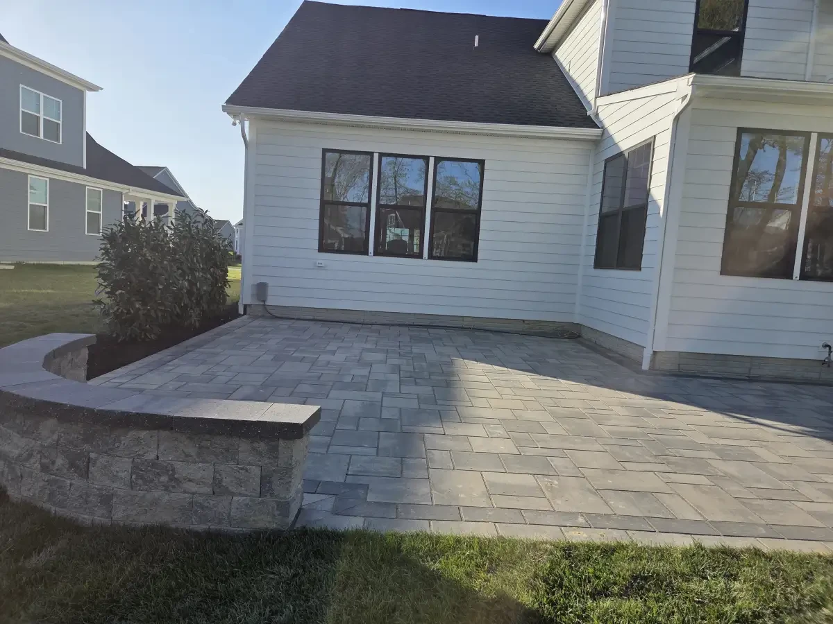 Paver courtyard and low wall beside a screened porch