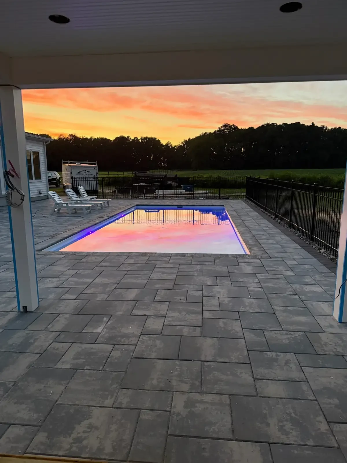 Illuminated swimming pool and paver deck at sunset
